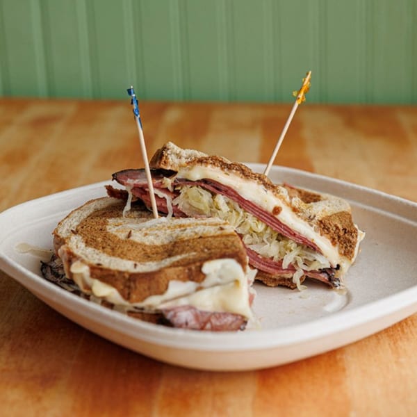 A sliced Reuben sandwich with corned beef, sauerkraut, and melted cheese on rye bread.
